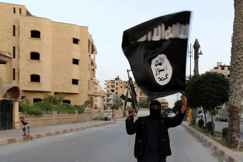 Image: A member loyal to the ISIL waves an ISIL flag in Raqqa